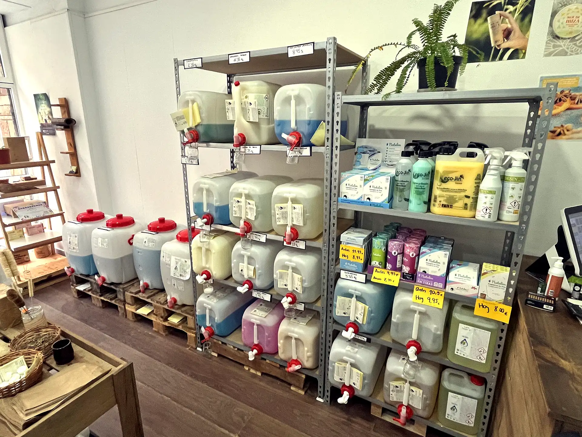 Estantería de la tienda de L'Aixeta Verda con los botes para la recarga de productos, tales como detergentes, suvizantes, fregaplatos, lavavajillas, quita grasas, quita manchas, limpiadores multi usos.